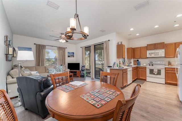 dining area featuring ceiling fan with notable chandelier and light hardwood / wood-style floors