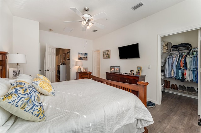 bedroom featuring a spacious closet, dark wood-type flooring, a closet, and ceiling fan