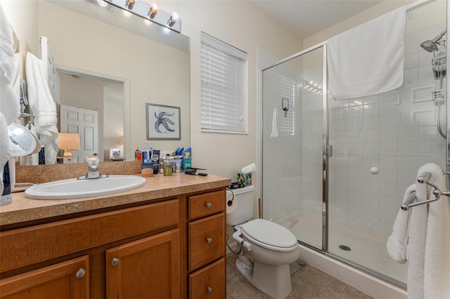 bathroom featuring toilet, vanity, a shower with door, and tile patterned flooring