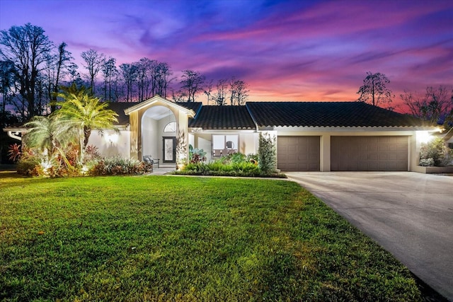 view of front facade with concrete driveway, a lawn, an attached garage, and stucco siding