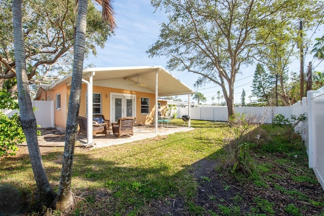 back of house with a lawn, french doors, ceiling fan, and a patio area