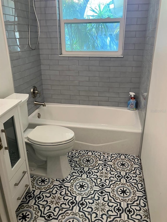 full bathroom featuring tiled shower / bath, tile patterned floors, toilet, and vanity