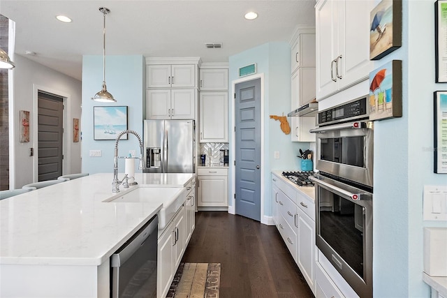 kitchen with stainless steel appliances, white cabinets, light stone counters, and decorative light fixtures