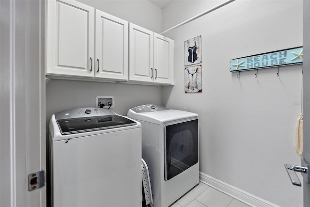 washroom with light tile patterned floors, cabinets, and washing machine and clothes dryer