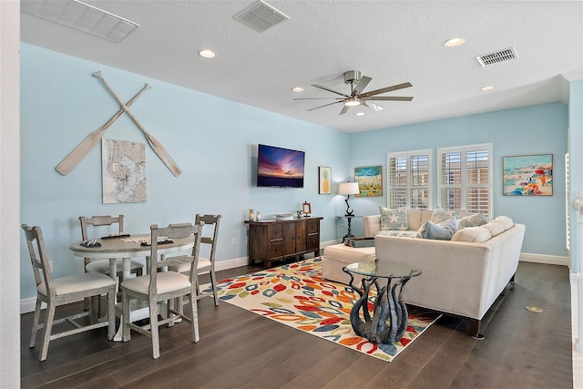 living room with dark wood-type flooring, ceiling fan, and a textured ceiling