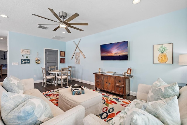 living room featuring dark wood-type flooring and ceiling fan