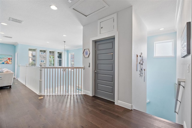 entrance foyer featuring ornamental molding, dark hardwood / wood-style floors, and a textured ceiling