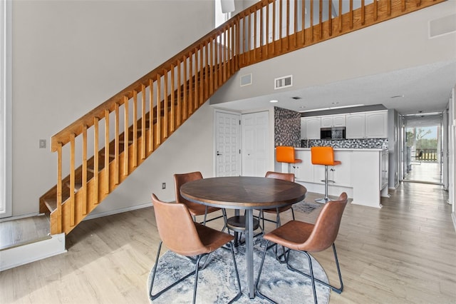 dining space with a high ceiling and light hardwood / wood-style flooring