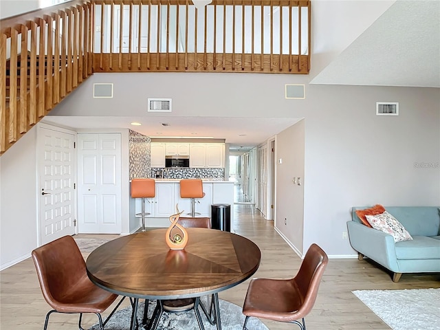 dining area with a high ceiling and light wood-type flooring