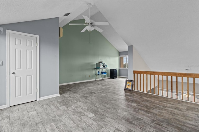 interior space featuring lofted ceiling, a textured ceiling, wood-type flooring, and ceiling fan