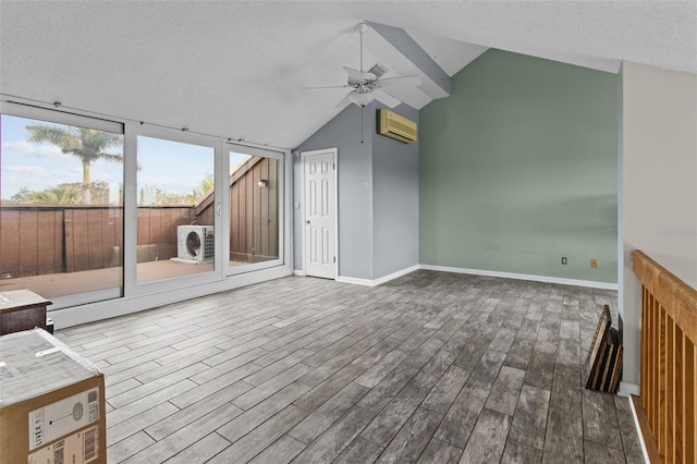 unfurnished living room with lofted ceiling, wood-type flooring, an AC wall unit, and ceiling fan