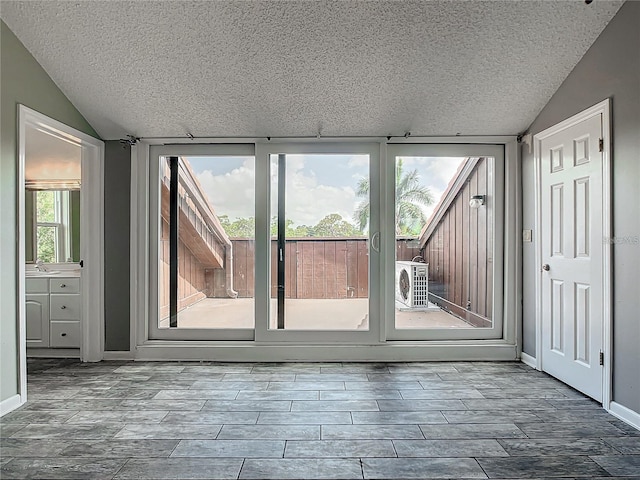 doorway featuring vaulted ceiling, ac unit, and a textured ceiling