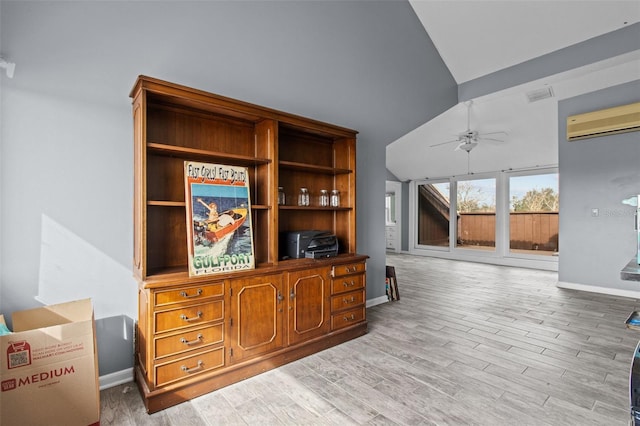 interior space with lofted ceiling, ceiling fan, a wall mounted AC, and light wood-type flooring