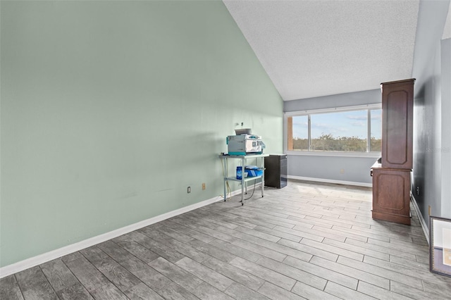 interior space with high vaulted ceiling, a textured ceiling, and light wood-type flooring