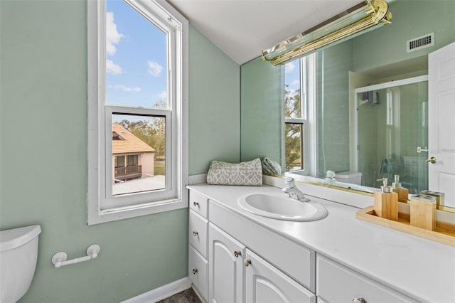 bathroom featuring a healthy amount of sunlight, toilet, a shower with shower door, and vanity