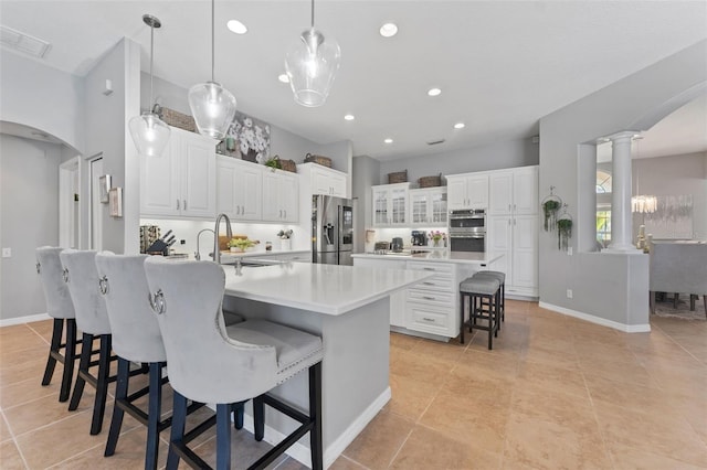 kitchen with a large island, hanging light fixtures, stainless steel appliances, and white cabinets