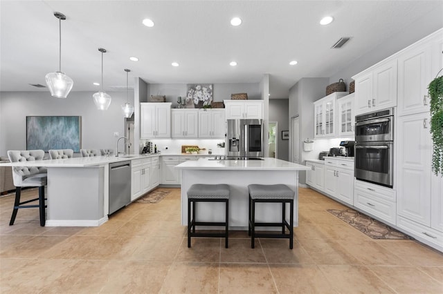 kitchen with a breakfast bar area, kitchen peninsula, a kitchen island, stainless steel appliances, and white cabinets