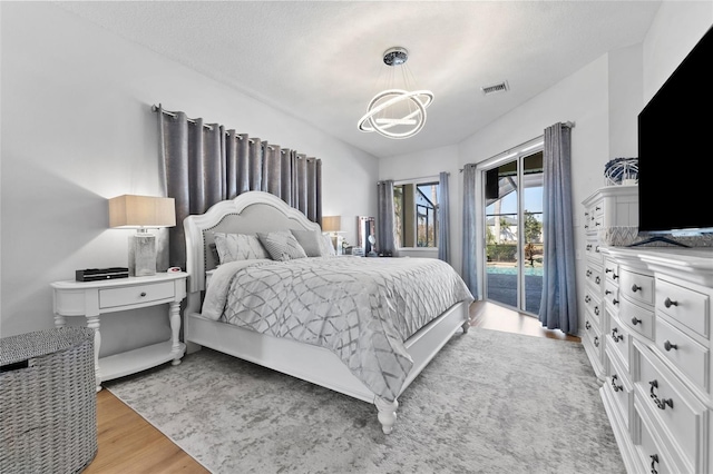 bedroom featuring an inviting chandelier, access to exterior, vaulted ceiling, and light wood-type flooring