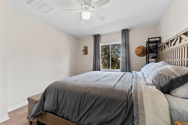 bedroom featuring ceiling fan, light hardwood / wood-style floors, and a textured ceiling