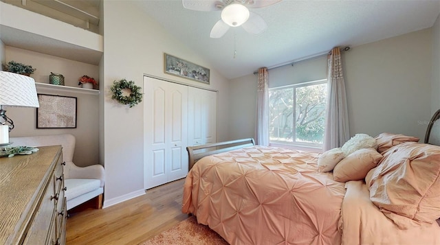 bedroom featuring vaulted ceiling, light hardwood / wood-style flooring, ceiling fan, a textured ceiling, and a closet