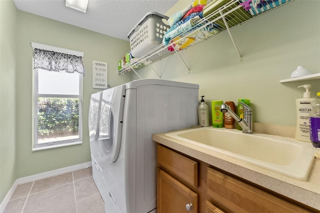 washroom featuring light tile patterned flooring, independent washer and dryer, sink, and a textured ceiling