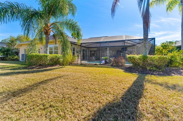 rear view of house with a lanai and a lawn