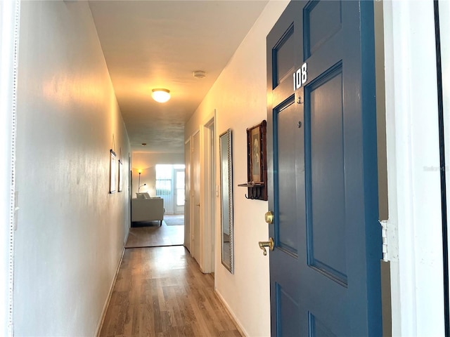 corridor with baseboards and wood finished floors