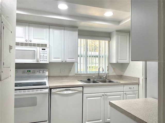 kitchen featuring white appliances, a sink, white cabinetry, and recessed lighting