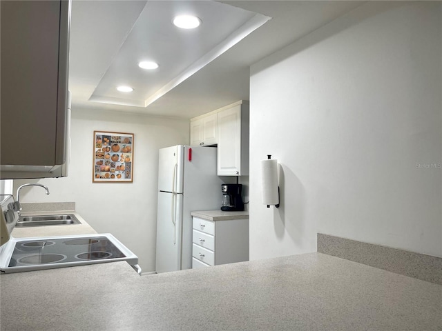 kitchen featuring range with electric cooktop, white cabinets, a raised ceiling, a sink, and recessed lighting