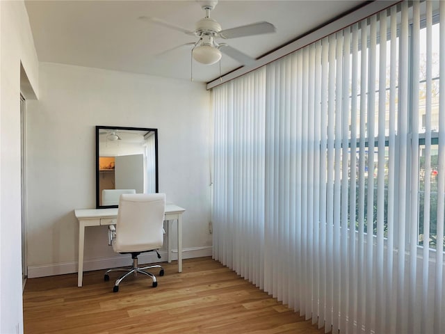 home office featuring light wood-style floors, baseboards, and a ceiling fan