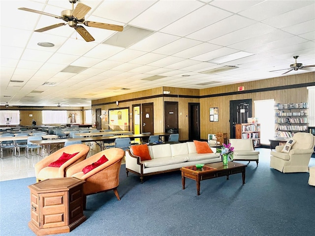 living room featuring ceiling fan, carpet flooring, and wooden walls