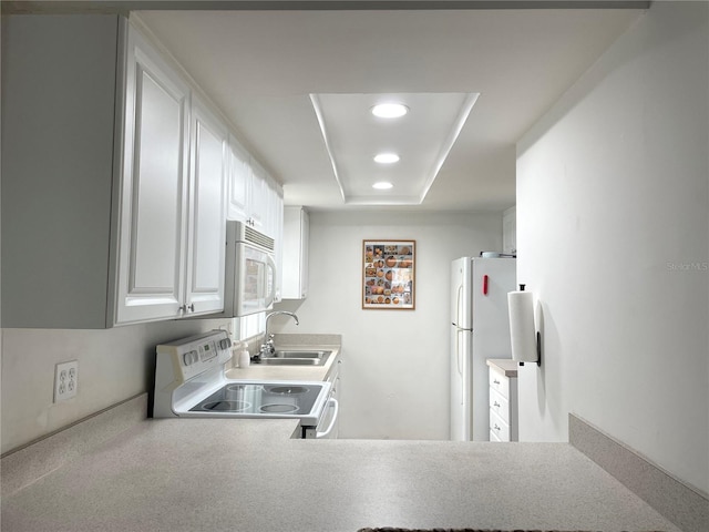 kitchen with recessed lighting, white appliances, a sink, white cabinetry, and a tray ceiling