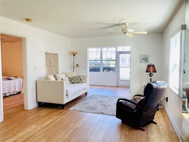 living room with ceiling fan, a wealth of natural light, and light wood-style floors