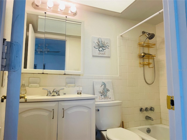 bathroom with toilet, vanity, tile walls, and shower / bathing tub combination