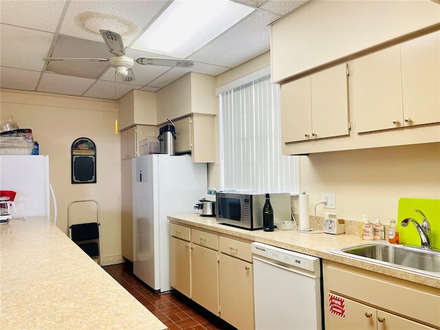 kitchen featuring white appliances, a ceiling fan, light countertops, a paneled ceiling, and a sink