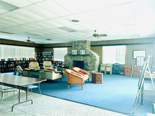 interior space featuring ceiling fan, speckled floor, a fireplace, and a drop ceiling