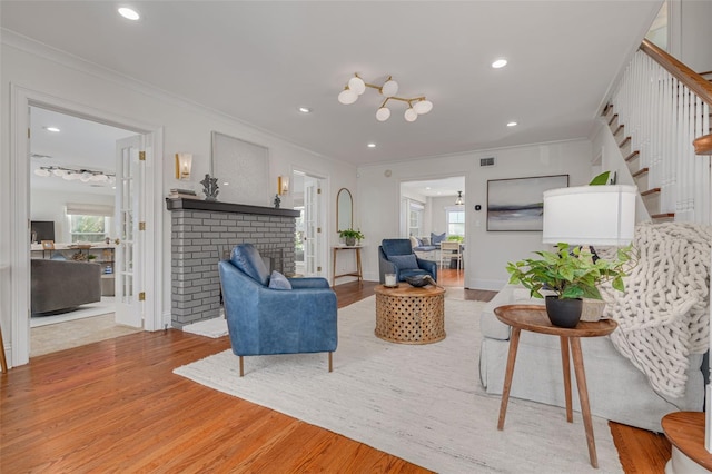 living room featuring crown molding, a fireplace, and light hardwood / wood-style floors