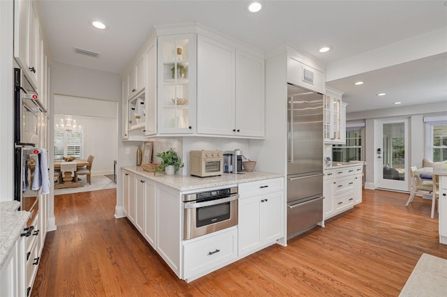 kitchen featuring built in refrigerator, white cabinets, and light wood-type flooring