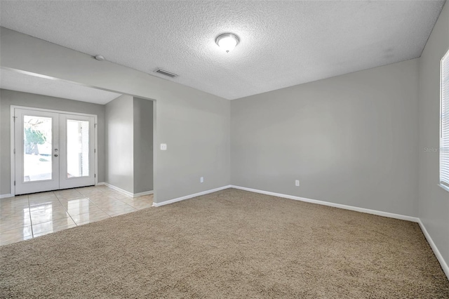 unfurnished room featuring light colored carpet, a textured ceiling, and french doors