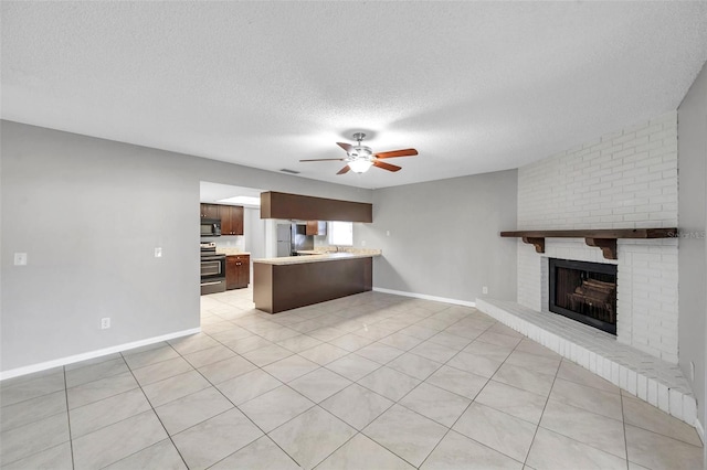 unfurnished living room with ceiling fan, a fireplace, a textured ceiling, and light tile patterned floors