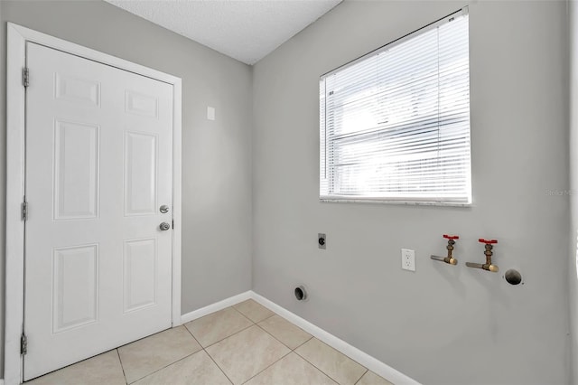 washroom featuring electric dryer hookup, a textured ceiling, and light tile patterned flooring