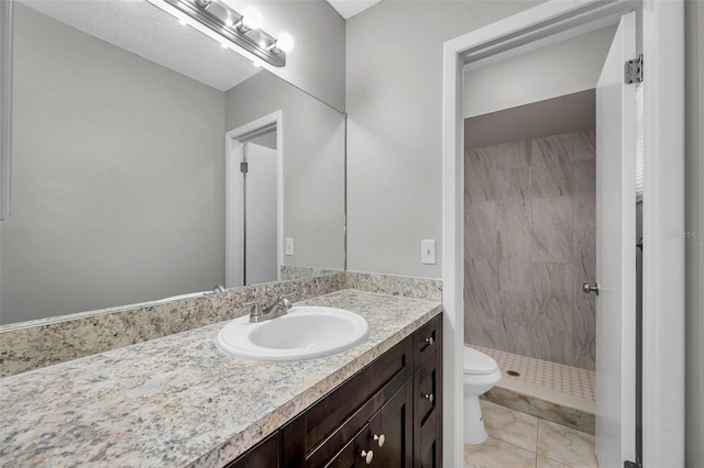 bathroom featuring vanity, tiled shower, tile patterned floors, and toilet