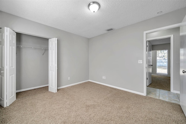 unfurnished bedroom featuring a closet, carpet, and a textured ceiling