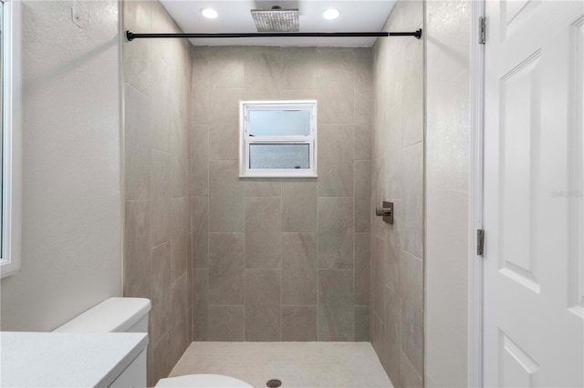 bathroom with tiled shower, vanity, and toilet