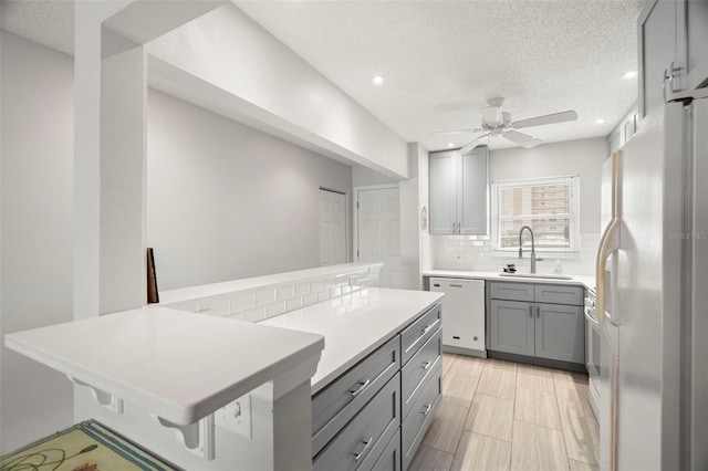 kitchen with sink, white appliances, tasteful backsplash, a kitchen bar, and kitchen peninsula