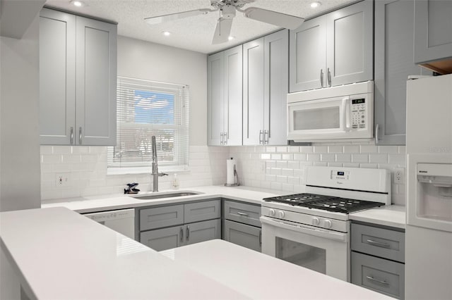 kitchen featuring sink, gray cabinetry, a textured ceiling, white appliances, and decorative backsplash