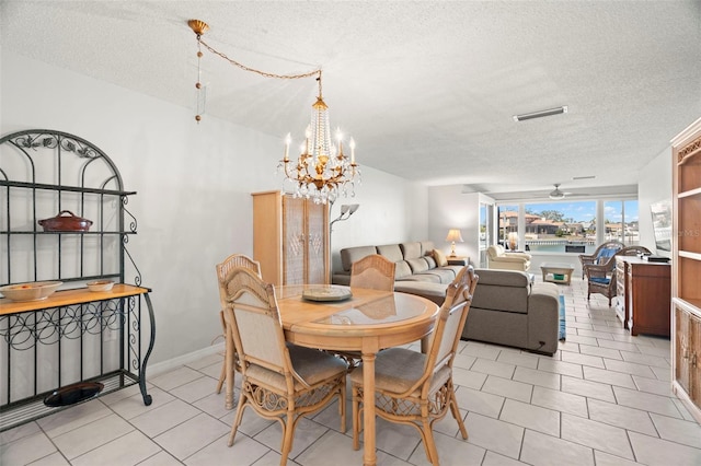 tiled dining area with ceiling fan with notable chandelier and a textured ceiling