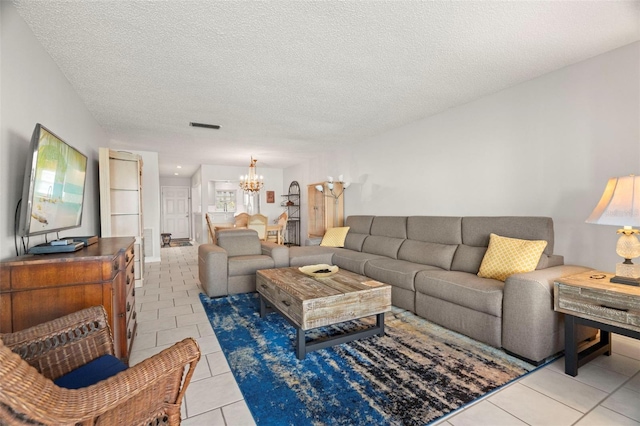 living room featuring light tile patterned floors, a notable chandelier, and a textured ceiling