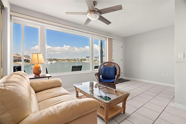 living room with light tile patterned floors, ceiling fan, a textured ceiling, and a water view