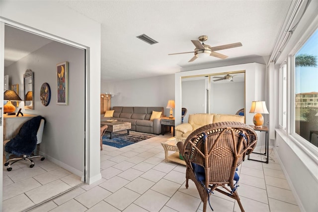 interior space featuring ceiling fan, light tile patterned floors, and a textured ceiling